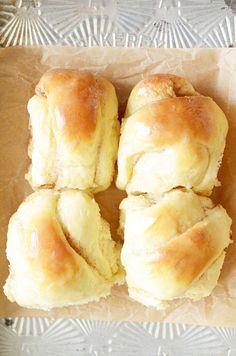 four rolls sitting on top of a piece of wax paper next to a glass plate