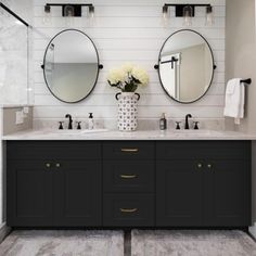 a bathroom with two sinks, mirrors and lights on the wall above them is decorated in black and white