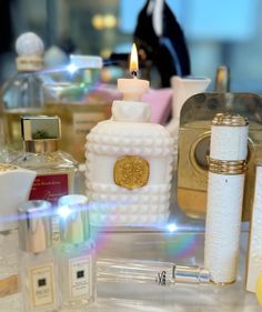 an assortment of perfume bottles and candles on a table