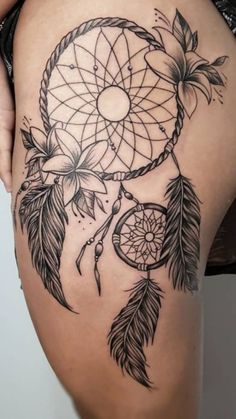 a woman's thigh with a tattoo that has a black and white dream catcher on it