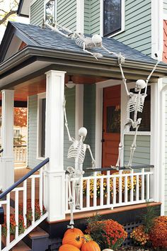 halloween decorations on the front porch of a house with skeletons and pumpkins in front