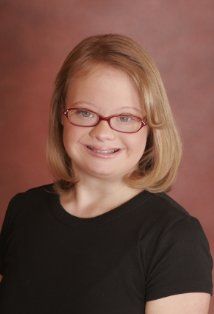 a woman with glasses is smiling for the camera while wearing a black t - shirt