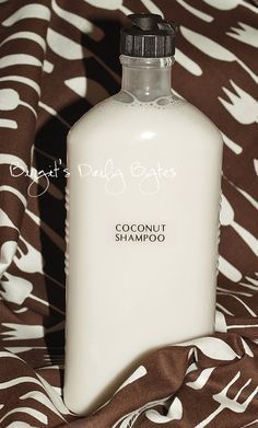 a bottle of coconut shampoo sitting on top of a brown and white bed spread