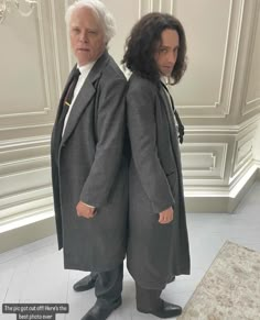 two men in long coats standing next to each other