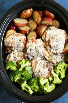 a bowl filled with meat, potatoes and broccoli on top of a blue table