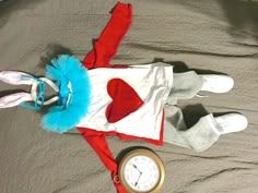 a child's costume laying on top of a bed next to an alarm clock