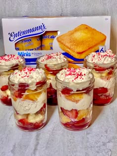 there are many desserts in glass jars on the table next to a box of cake mix