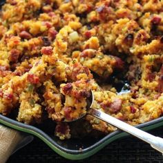 a casserole dish with meat and vegetables in it on a cloth napkin next to a spoon