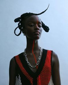 a woman with braids on her head wearing a red and black dress, necklace and earrings