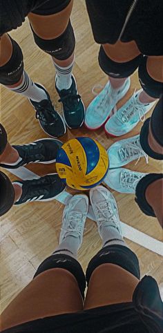 a group of people standing in a circle with a ball on the floor next to them