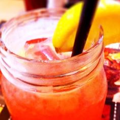 a close up of a drink in a glass with a straw and lemon wedges