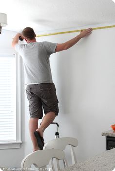 a man measuring the wall with a tape measure