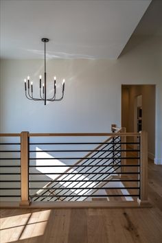 a chandelier hanging from the ceiling in a room with hardwood floors and white walls