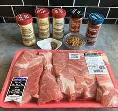 raw meat on a tray next to spices and seasonings for steaks in the kitchen