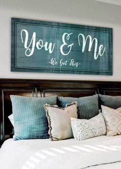 a bed with pillows and a wooden sign above it that says you & me we got this