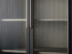 an empty glass cabinet with metal bars on the doors and bottom shelf in front of it