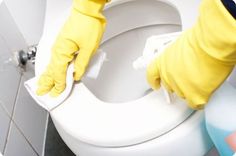 a person in yellow gloves cleaning a toilet