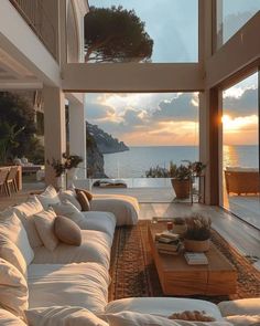 a living room filled with lots of furniture next to a large open floor plan overlooking the ocean