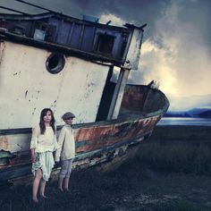 two people standing in front of an old boat