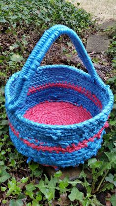 a blue and red basket sitting in the grass