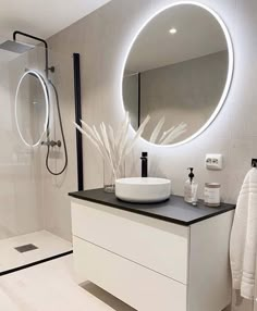 a bathroom with a round mirror above the sink and a black counter top under it