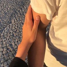 a person with their arm around another persons leg on a cobblestone road in the sun