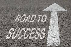 road to success written on asphalt with an arrow pointing up