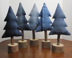 five small trees made out of jeans on wooden bases, sitting on a wood table