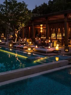 an outdoor lounge area with lit candles around the pool