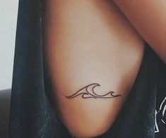 a woman's arm with a tattoo on it and a wave in the background