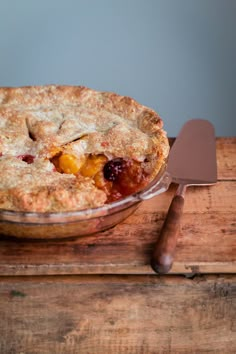 a pie sitting on top of a wooden table next to a spatula and knife