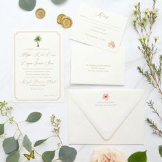 the wedding stationery is laid out with flowers and greenery