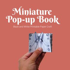 the miniature pop - up book black and white printable paper craft is being held by a hand