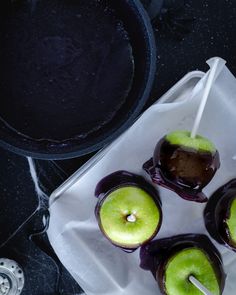 four green apples sitting on top of a white paper towel next to a black pan