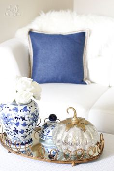 a blue and white tray with two vases sitting on top of it next to a couch