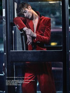 a man in a red suit leaning up against a glass door with his hands on his head