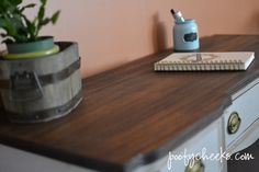 a wooden desk with a potted plant on it and a notebook next to it