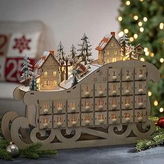 a wooden calendar with houses and trees on it next to a christmas ornament