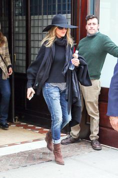 a woman walking out of a building with a hat on