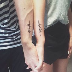 two people are holding hands with tattoos on their arms and the words love written in cursive letters