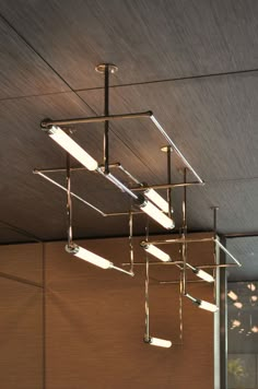 a suspended light fixture in a room with wood paneling and metal bars hanging from the ceiling