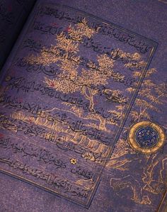 an open book with arabic writing on the cover and gold trimmings, sitting on a table