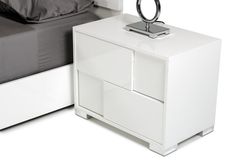 a white night stand next to a bed