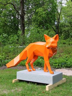 an orange paper fox statue in the grass