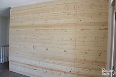 a wooden wall in a room with hard wood flooring and white trim on the walls