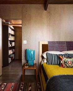 a bedroom with wood paneling and colorful pillows on the bed, along with bookshelves