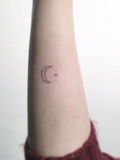 a woman's arm with a small crescent tattoo on it