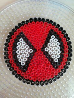 a beaded spiderman face is shown on a glass plate with black, white and red beads