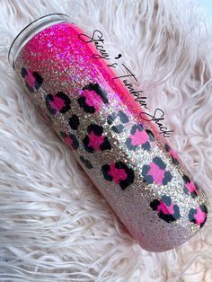 a pink and black leopard print tumbler with glitter on the lid sitting on a fluffy white blanket