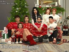 a group of people dressed in christmas sweaters sitting on the floor next to a christmas tree